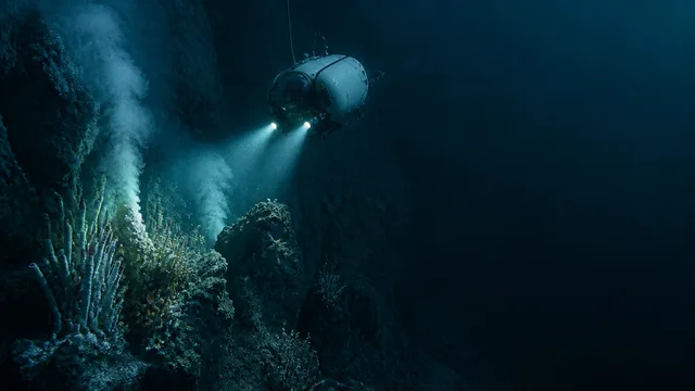A man points toward a glowing submersible between deep ocean cliffs beside EARTH’S DEEPEST POINT text