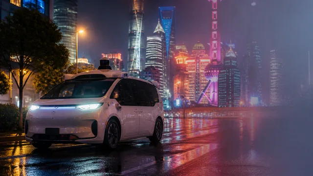 White and blue autonomous vehicle with cartoon character branding speeds through urban street with BBC News logo and…