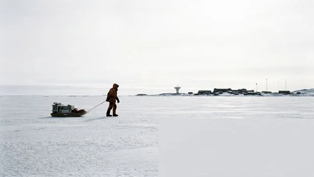 Woman in red jacket and headband smiles at camera with snowy Antarctic landscape and mountain behind her, text reads "We…