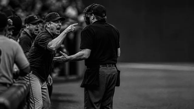 Baseball manager in Pirates cap yelling with mouth wide open, text overlay reading "EJECTED FOR YELLING," with smaller…